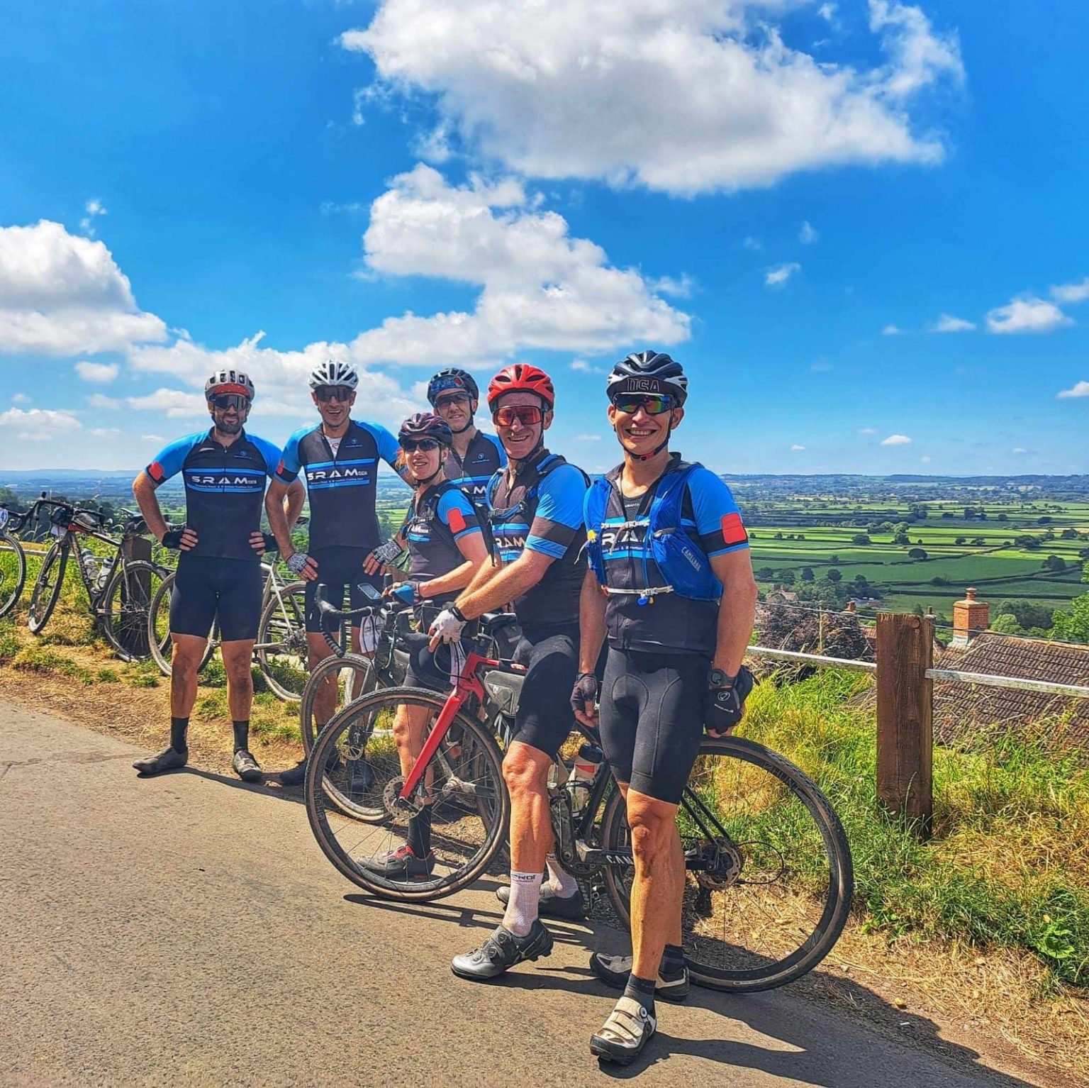 A group of SRAMcc riders in club kit at a roadside viewpoint